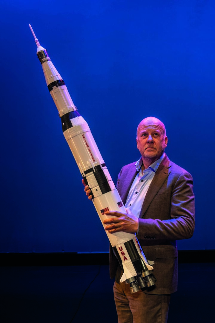 Diederik van Vleuten met een witte raket in zijn handen en hij kijkt omhoog.